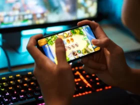 Χέρια παίζουν παιχνίδι σε smartphone, με φωτισμένο πληκτρολόγιο gaming στο…